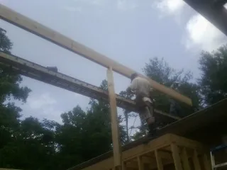 Carpenter setting a ridge beam over a new addition frame — Ice Dam Removal by Roofing Brothers in Centereach