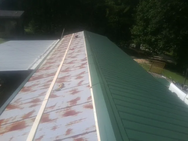 Old rusted panels beside newly installed green metal roofing — Wind Damage Roof Repair by Roofing Brothers in Centereach