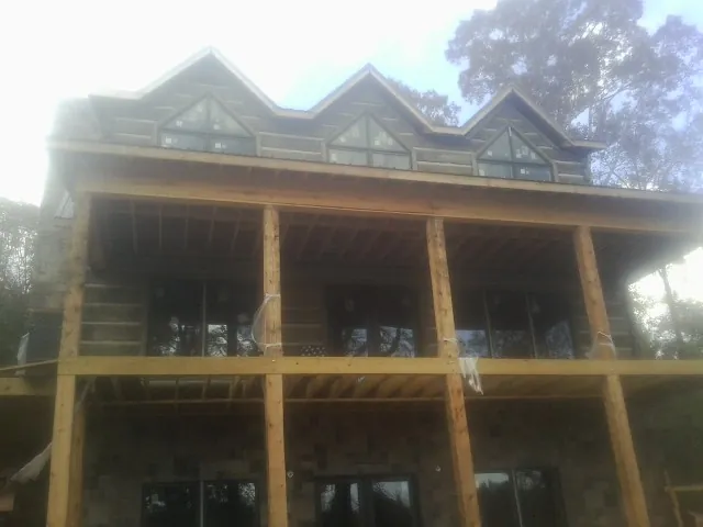 Dormers and porch framing on a large log home under construction — Roof Coating work by our crew in Centereach