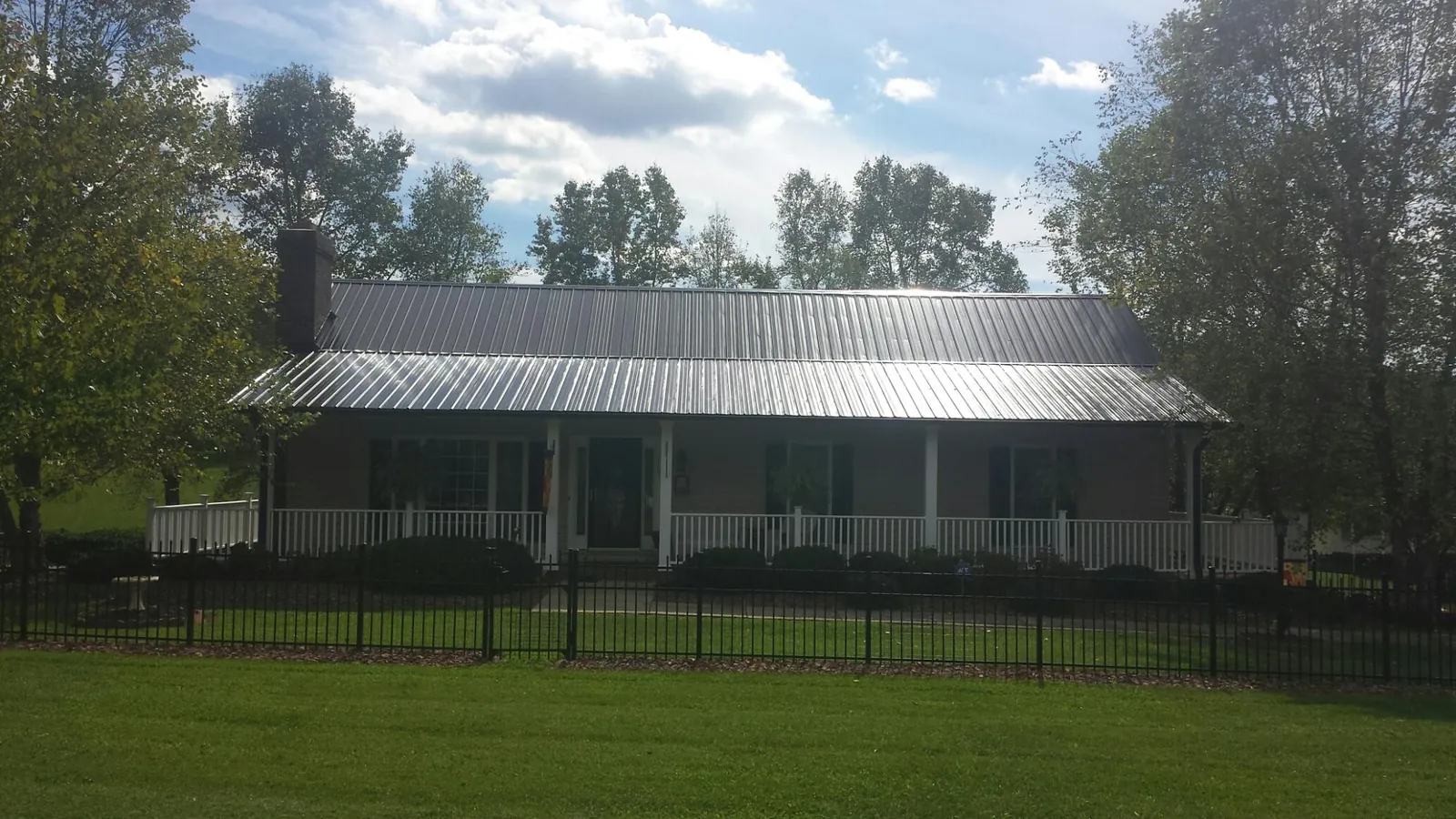 Gray metal roof on a brick ranch with a full width front porch — Gutter Guard Installation work by our crew in Centereach