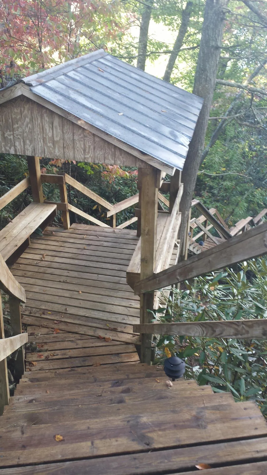 Metal roofed shelter over wooden steps on a wooded walkway — Skylight Repair & Installation work by our crew in Centereach