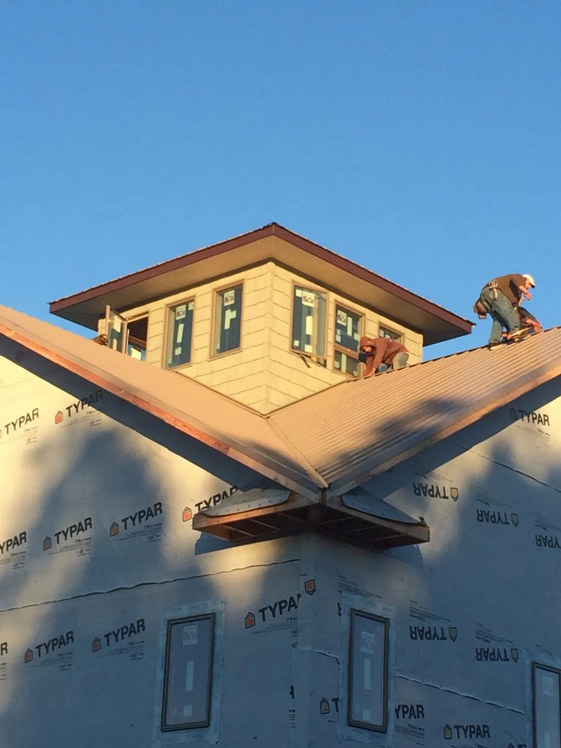 Roofers working around a rooftop cupola on a new metal roof at sunset — Roof Waterproofing in Centereach by Roofing Brothers